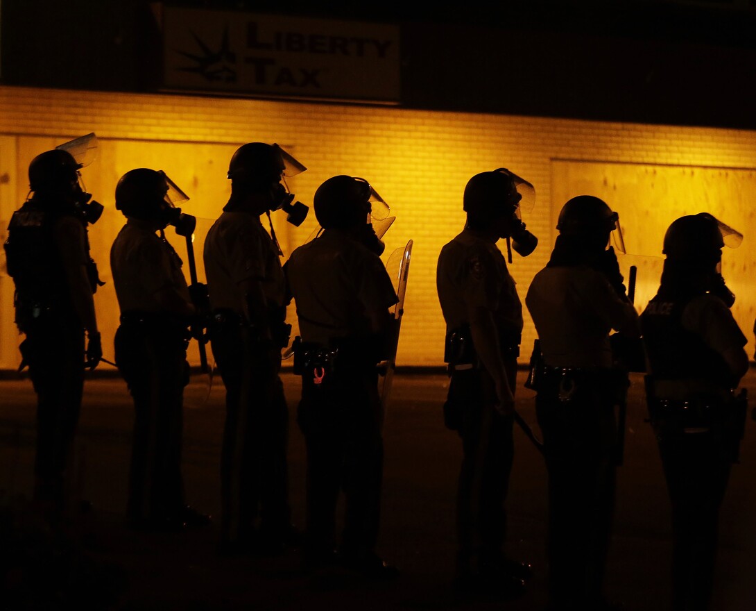 Police in Ferguson, Mo., wait to advance after tear gas was used to disperse a crowd Sunday, Aug. 17, 2014, druing a protest for Michael Brown.